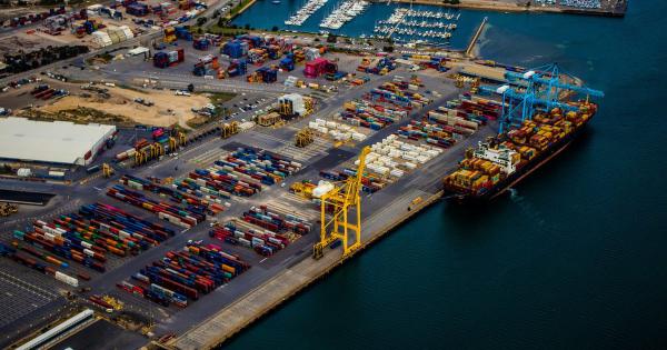 Aerial view of a container terminal, with thousands of containers stacked across the yard, a single ship alongside being loaded, and an idle crane on the quay